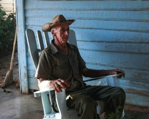 Old Man Sitting in Cowboy Hat Sitting in Chair Outdoors